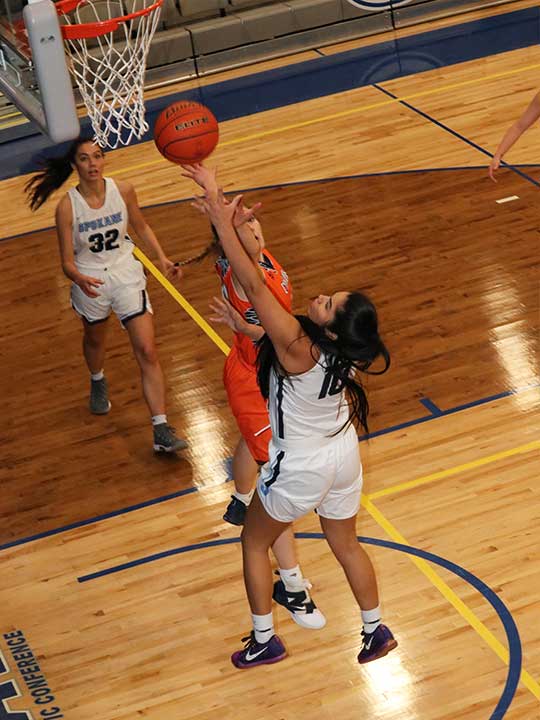 Women's basketball player shooting for the hoop against opponent
