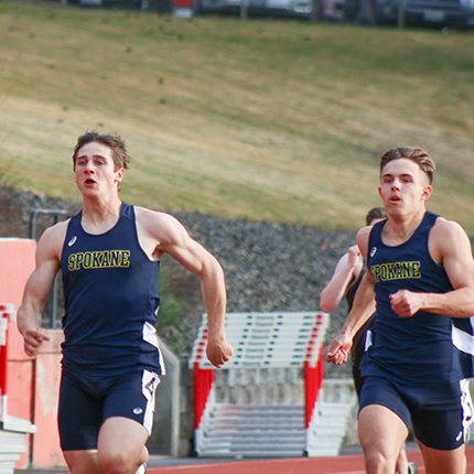 Two sasquatch men wearing blue running tank tops and blue shorts running on the track. 
