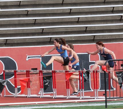 Track athlete jumping over the hurdle