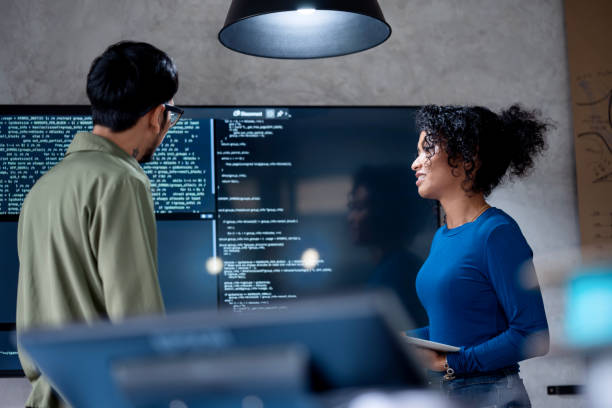 A man and a woman review code on a screen