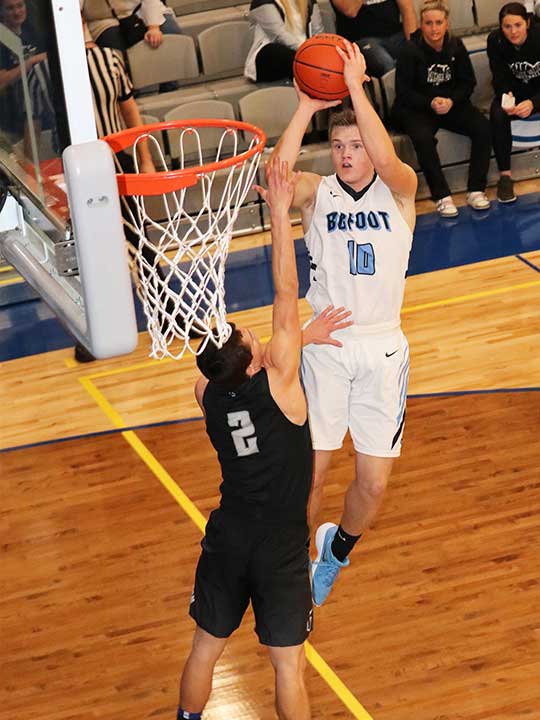 Men's basketball player going for the shot against opponent with hoop in sight. 