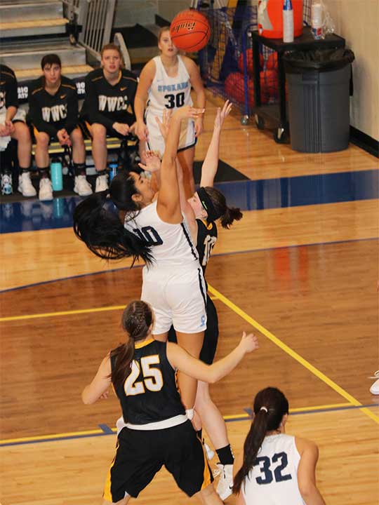 Women's Basketball player shooting for the hoop over opponents heads