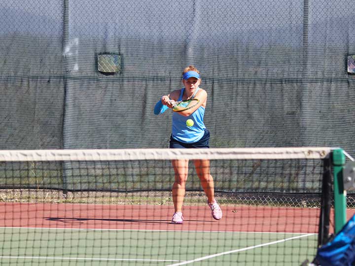 Women's tennis player returning the ball with and underhanded hit