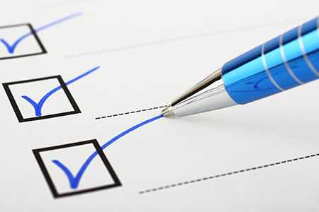 A pen filling out checkmarks on a checklist.
