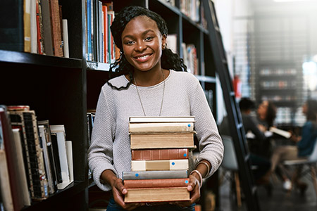 Librarian holding books in a library isle