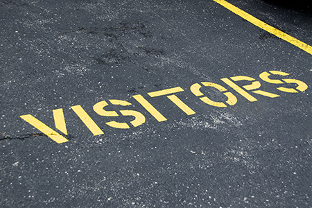 The word visitors painted on the asphalt of a parking space